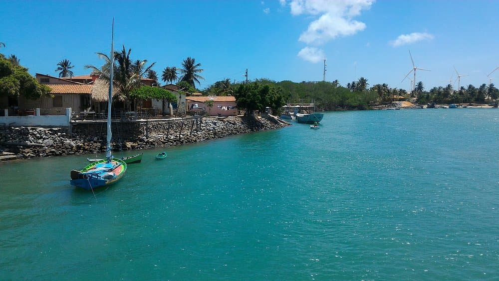 Jangada de pesca ancorada no estuário de Mundaú, com a vila e o manguezal ao fundo